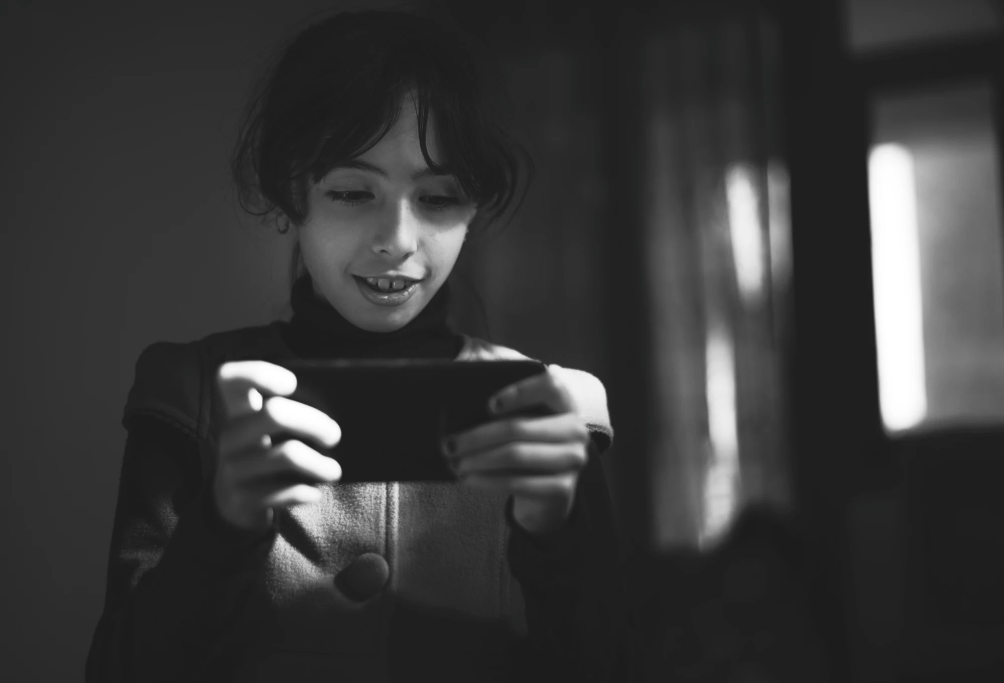 Un enfant utilise un smartphone dans la pénombre.